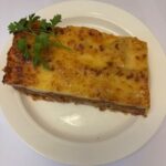 Lunch lasagne med tilbehør av salat, baguette og smør